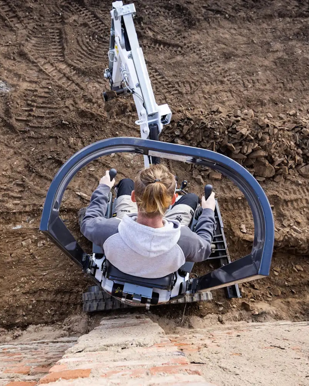 Overhead view of an operator skilfully controlling the Bobcat E10 Mini Excavator, highlighting its precise handling and suitability for detailed excavation work.