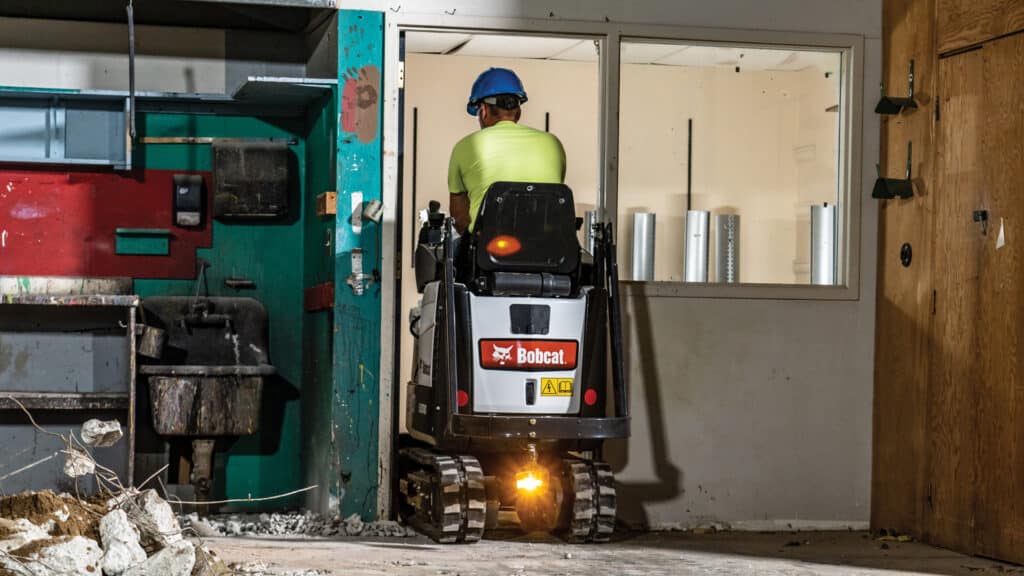 Bobcat E10 Mini Excavator navigating effortlessly through a narrow indoor space, showcasing its compact design and manoeuvrability for confined job sites.