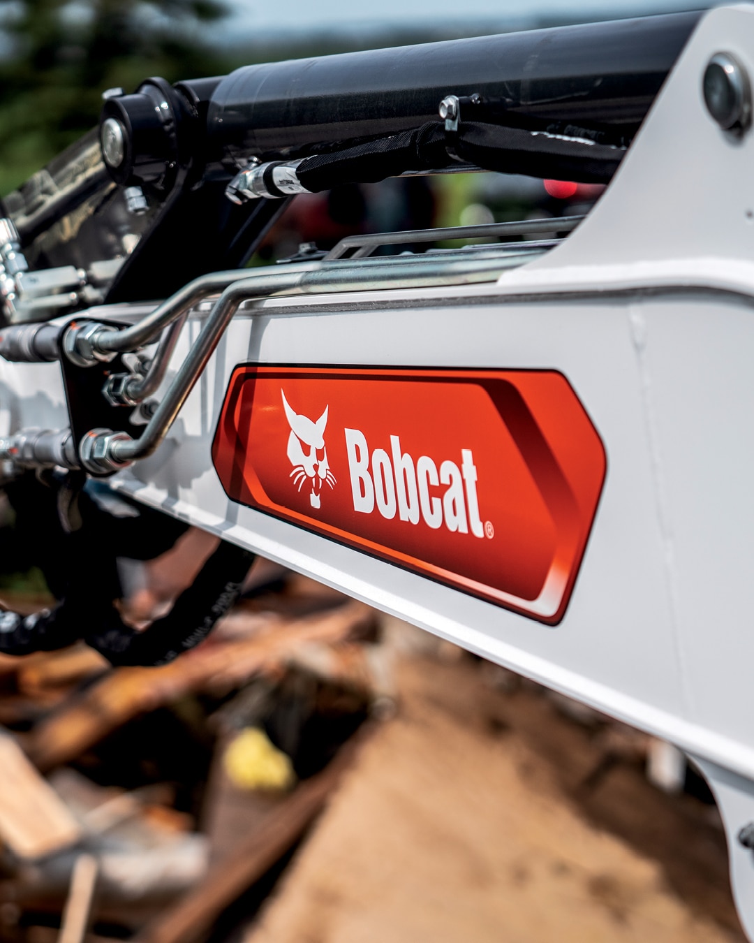 Close-up shot of the hydraulic arm of a Bobcat E60 Mini Excavator, highlighting the bold red Bobcat branding, emphasising the equipment's strength and reliability.