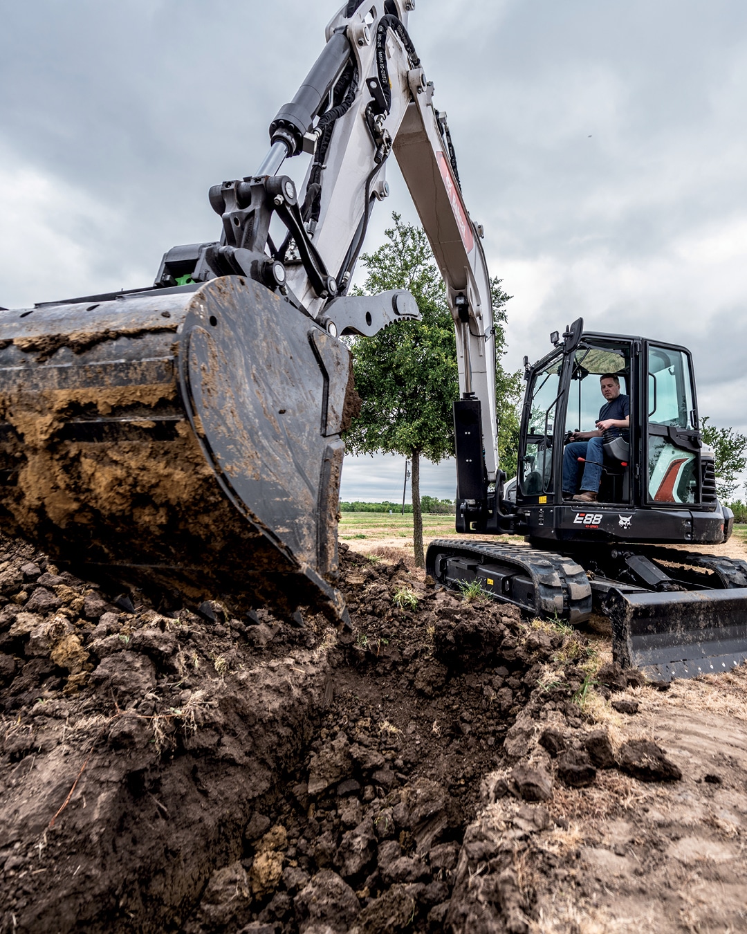 A Bobcat E88 Mini Excavator in action, with its operator efficiently digging in a challenging environment, highlighting its power and precision for demanding earthmoving tasks.