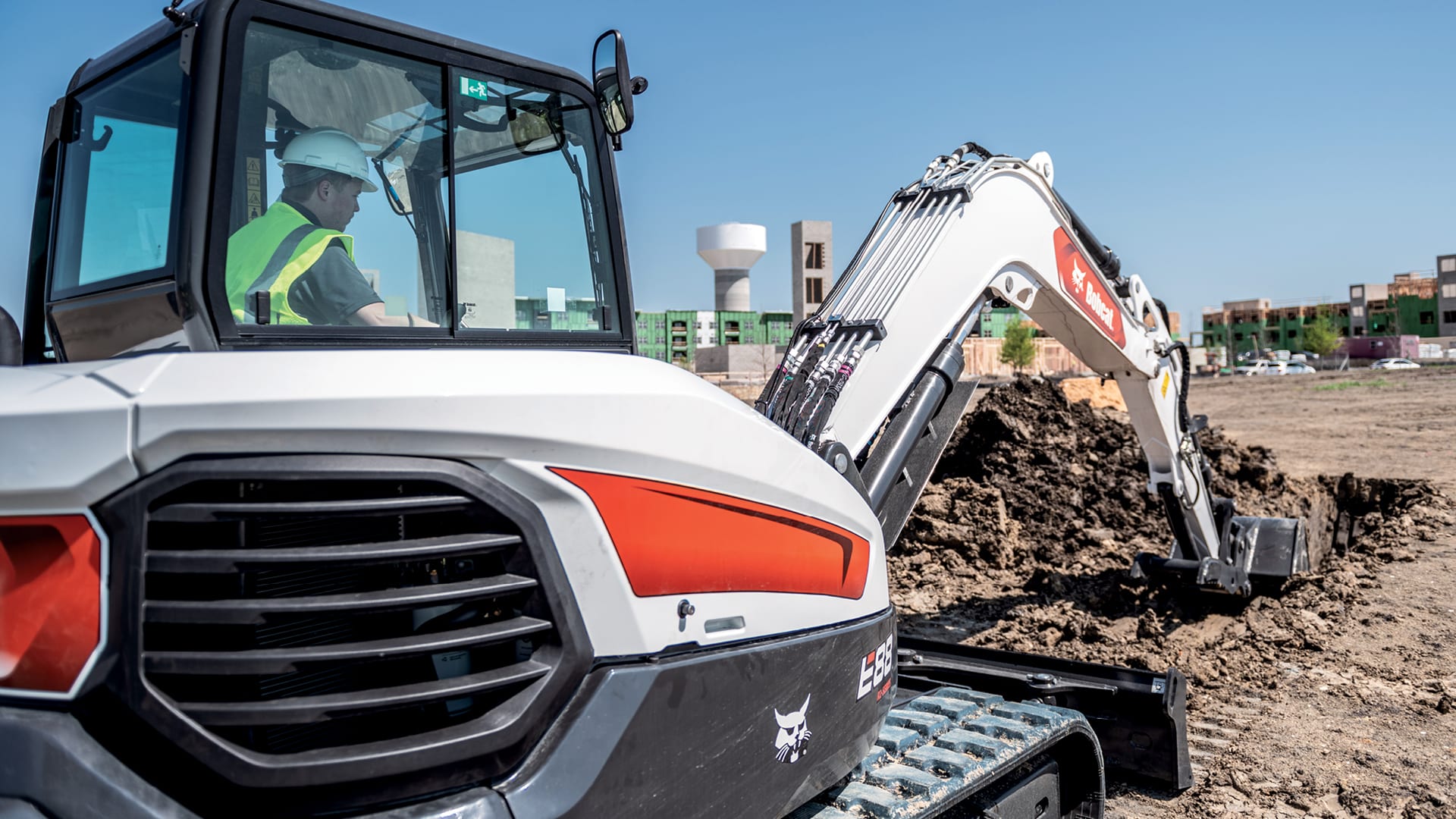 A Bobcat E88 Mini Excavator in action at a construction site, highlighting its operator-focused cabin design and advanced hydraulic system, ideal for precise digging and trenching tasks in urban development environments.