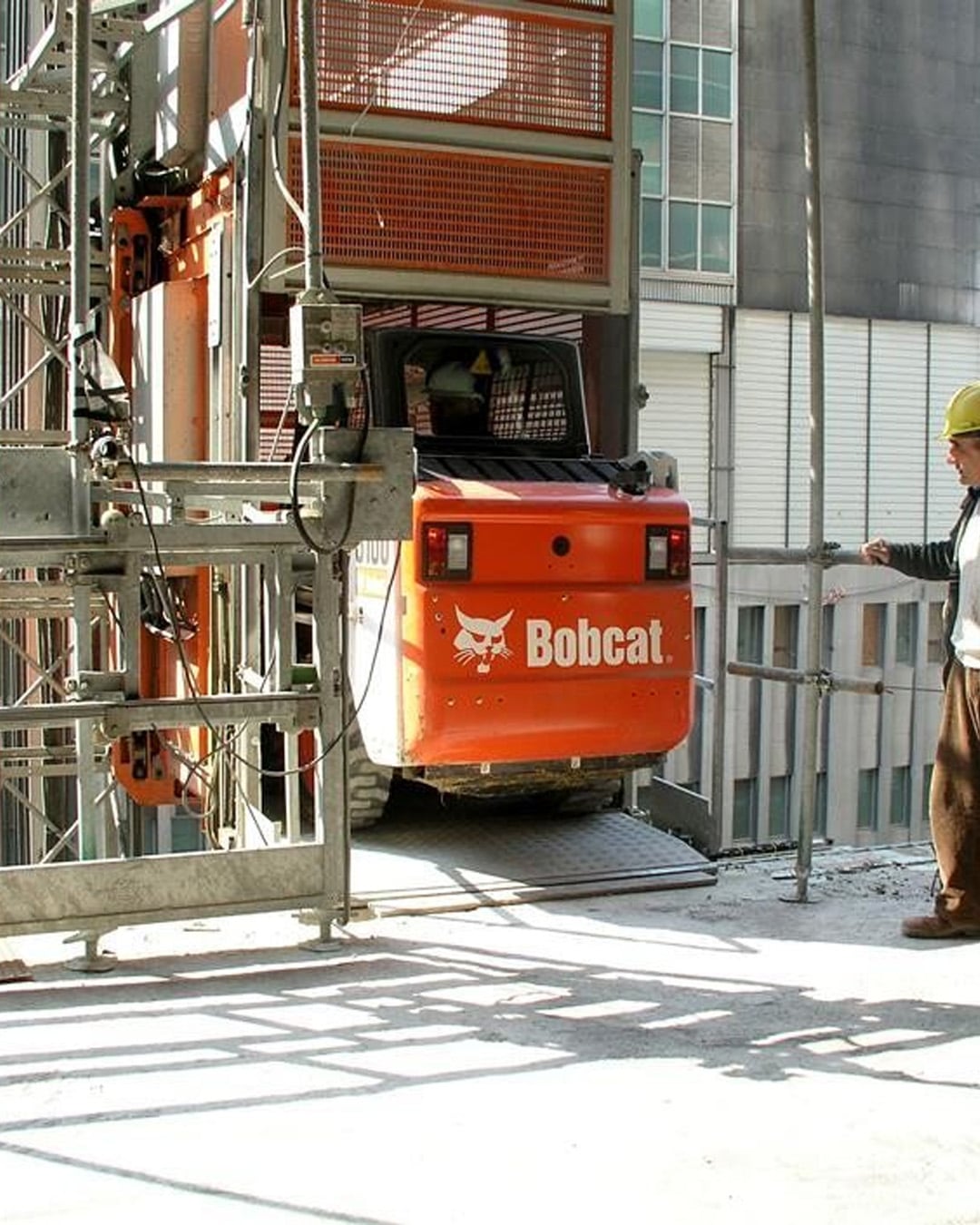 Bobcat S100 Skid Steer Loader being lifted on a construction hoist to a high-rise building site, showcasing its compact size and manoeuvrability in urban environments.
