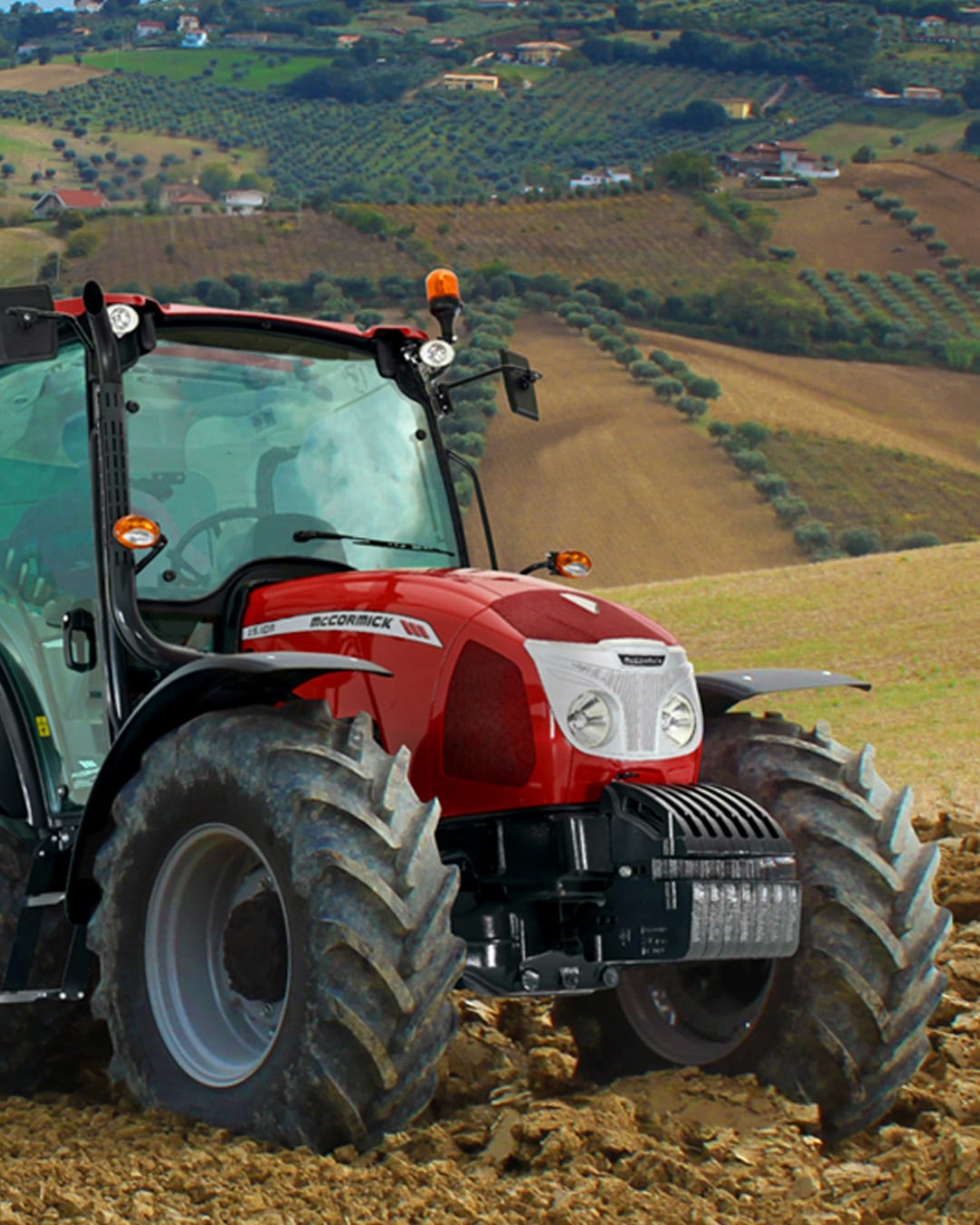 McCormick X5 Farm Tractor working on a hillside field surrounded by olive groves and rolling farmland, highlighting its performance in Mediterranean-style terrain.