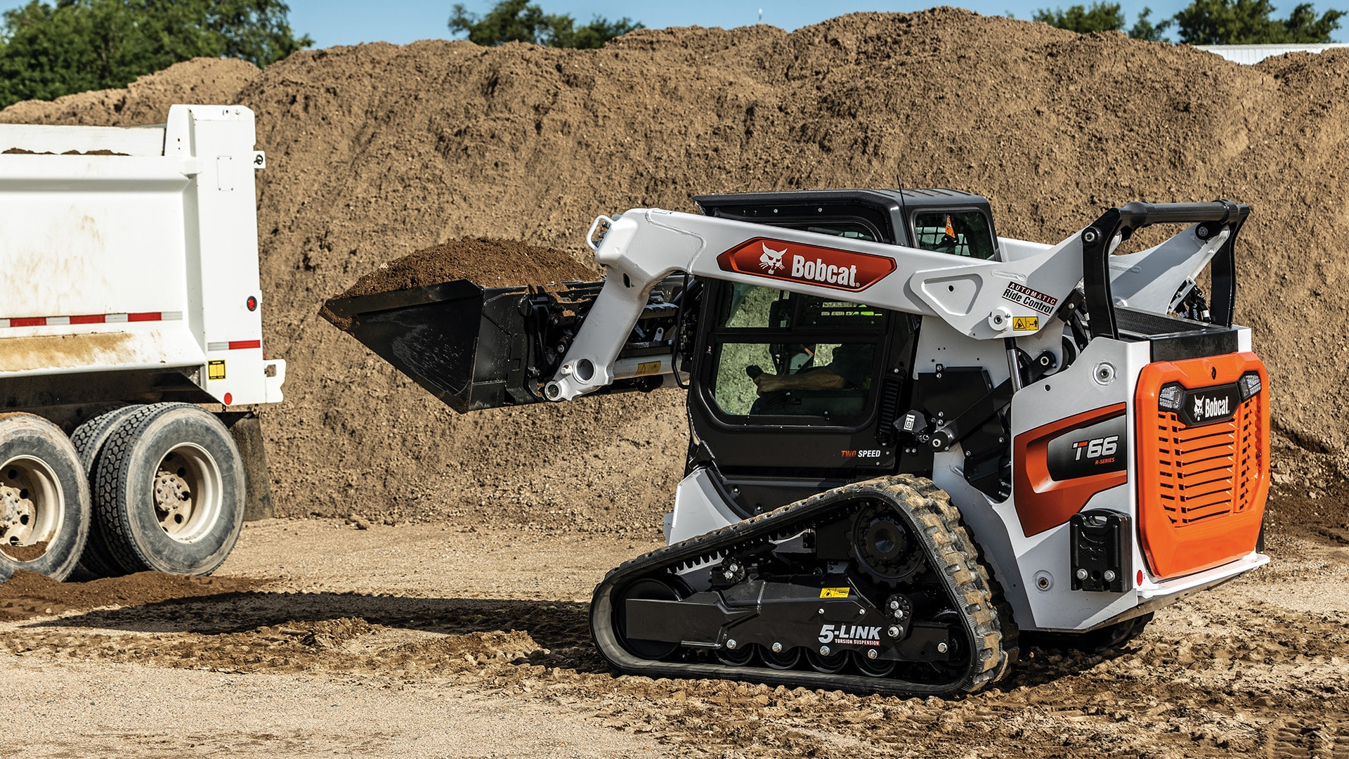Bobcat T66 Track Loader loading dirt into a dump truck, demonstrating powerful lifting and material handling capabilities on a construction site.