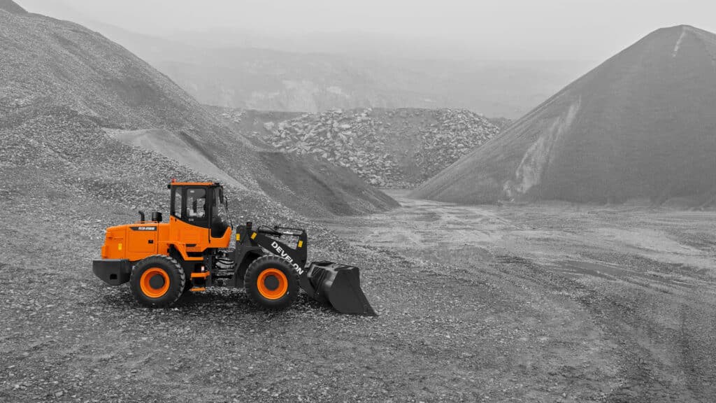 A Develon SD200 Wheel Loader working in a vast gravel quarry, highlighting its durability and efficiency in large-scale material handling and mining applications.