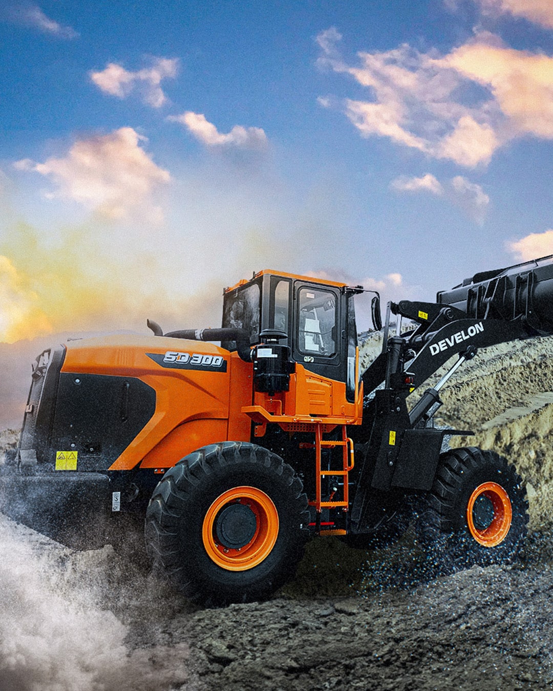 A Develon SD300 Wheel Loader powering through rugged terrain at sunset, equipped with a large front bucket, built for high-performance material handling in challenging worksite conditions.