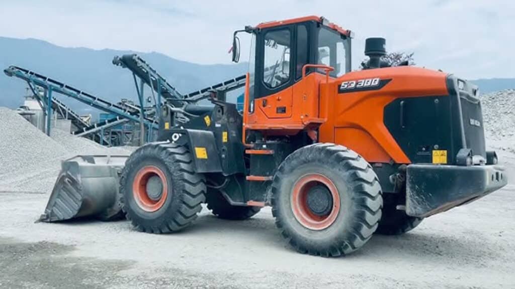 A Develon SD300 Wheel Loader parked at a quarry site, equipped with a large front bucket, designed for powerful and efficient material handling in tough industrial environments.