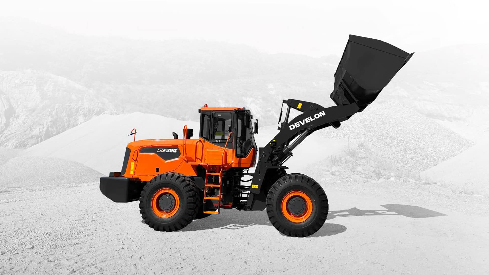 A Develon SD380 Wheel Loader with its front bucket raised, operating on a quarry site, highlighting its strength and versatility for heavy material handling.