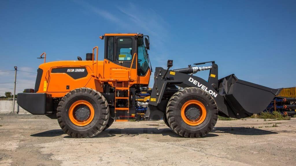 A Develon SD380 Wheel Loader parked on a construction site, featuring a large front bucket and rugged build for heavy-duty loading and material handling tasks.