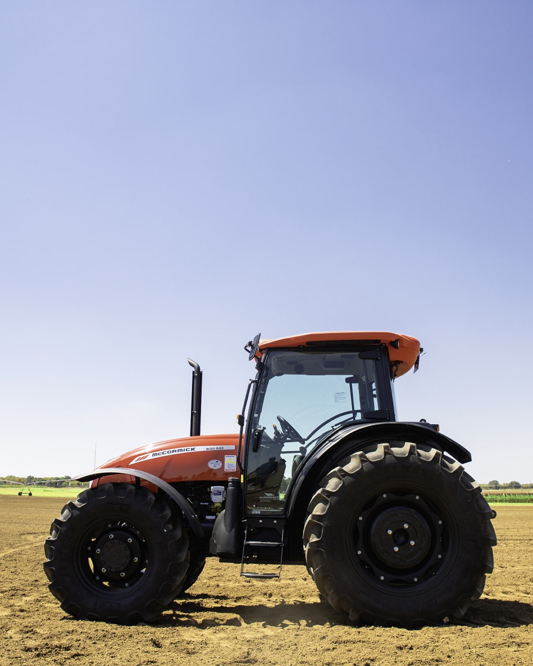 McCormick tractor parked on freshly tilled soil under a clear blue sky.