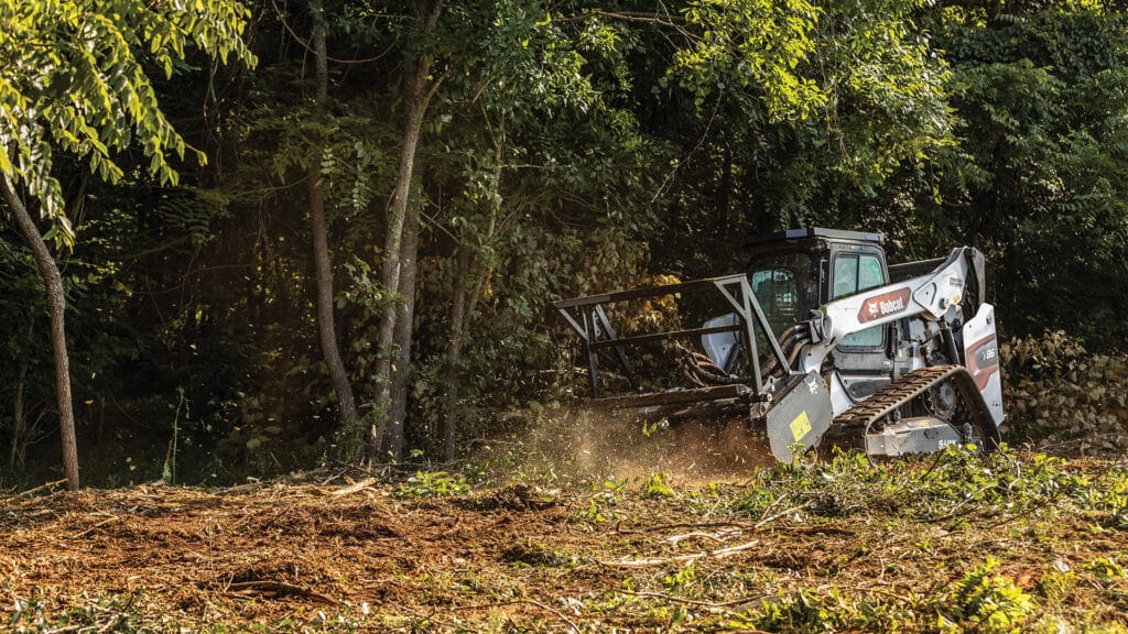 A Bobcat Track Loader clearing dense vegetation with a forestry attachment, demonstrating its power and efficiency in land management tasks.