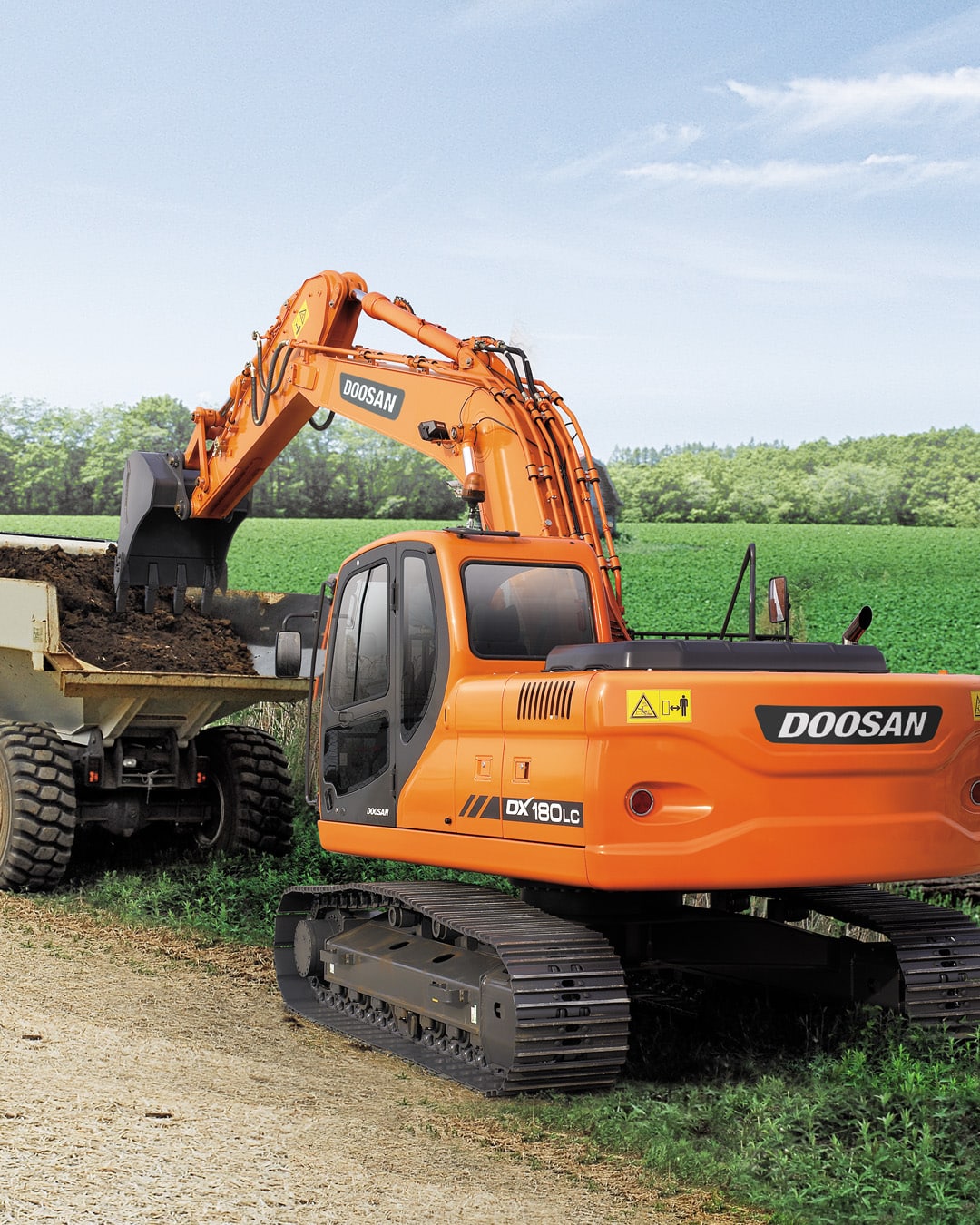 Develon DX225LC-7M Large Excavator efficiently loading soil into a dump truck on a farm, showcasing its versatility and power in agricultural settings.