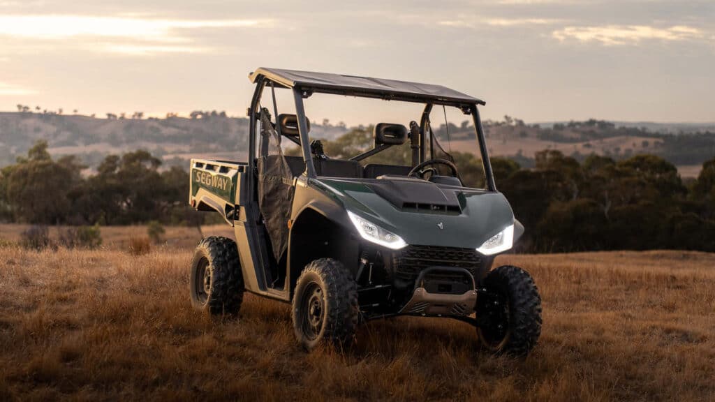 Segway UT6 Rugged EPS UTV parked in an open paddock at dusk with headlights on, highlighting its robust frame and off-road capability in a rural landscape.