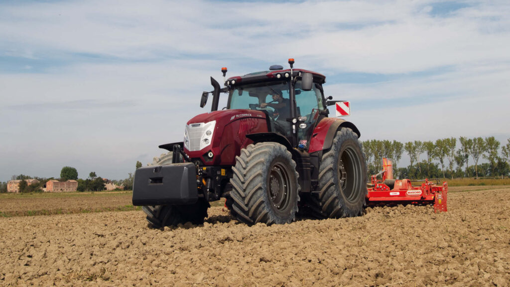 McCormick X7 Series tractor operating in a dry paddock with a red rotary tiller, showcasing heavy-duty performance as part of Delecca’s 0.99% finance campaign.