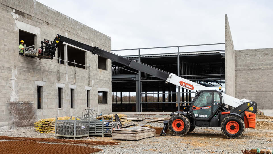 Bobcat T40.180 telehandler for sale lifting workers and materials on a construction site, showing long reach and stability for building projects.