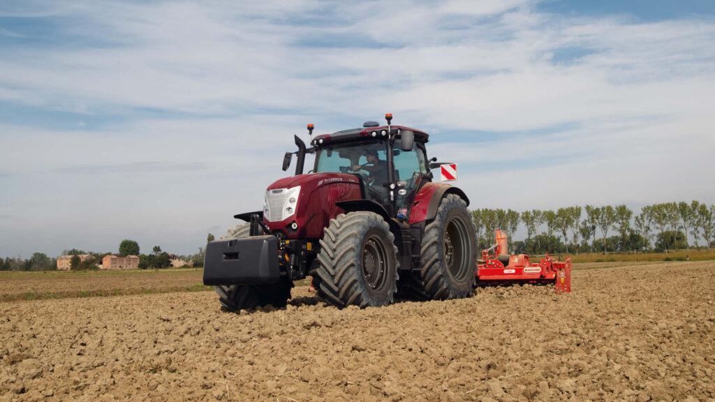 McCormick X7 tractor cultivating soil in a paddock with a red implement attached on a farm.