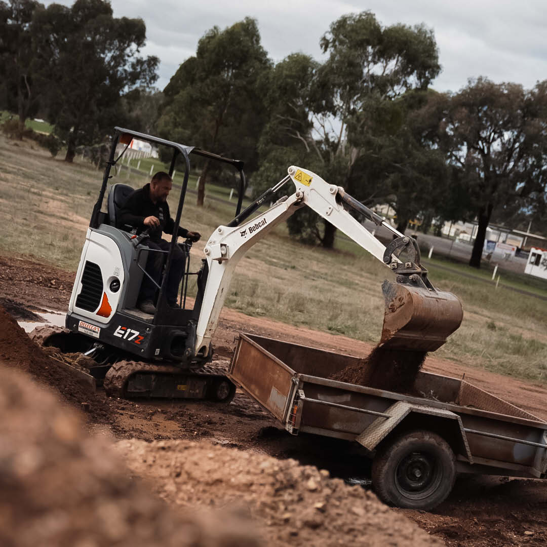 Bobcat E17 Mini Excavator loading dirt into a trailer.