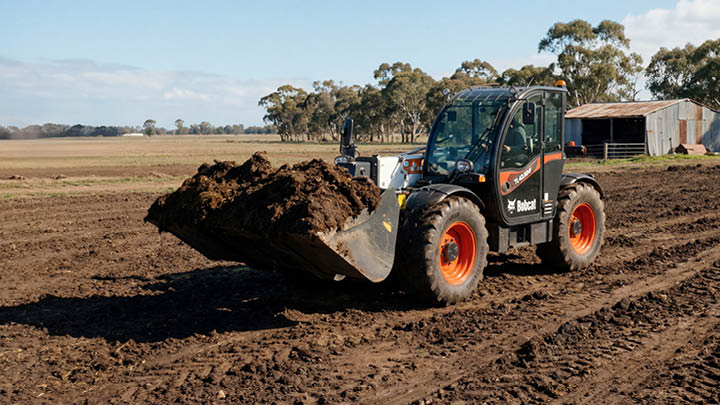 Bobcat agricultural telehandler loading composted manure with bucket attachment on Central Victoria farm