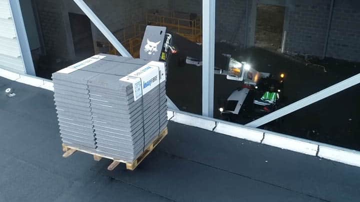 Bobcat construction telehandler lifting pallet of insulation panels to upper floor of multi-storey commercial building showing material distribution capability