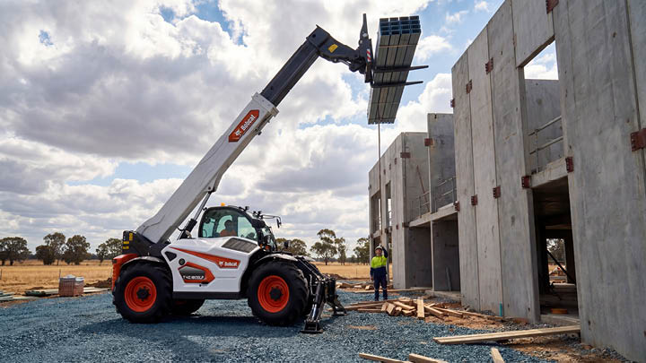 Bobcat T40.180SLP construction telehandler lifting a bundle of steel purlins to the top of a tilt-panel concrete commercial building on a construction site in Central Victoria