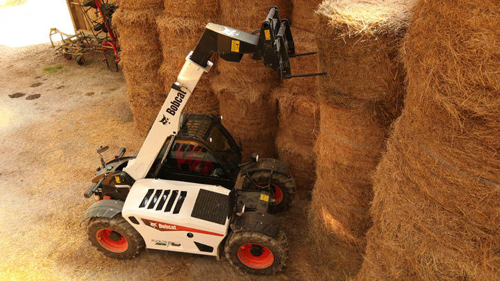 Bobcat TL30.60 agricultural telehandler stacking hay bales in low-height farm shed