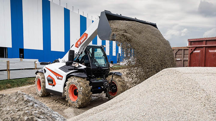 Bobcat TL30.60 construction telehandler loading aggregate with bucket attachment at an industrial building site