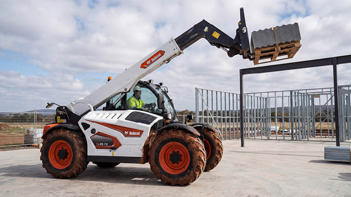 Bobcat TL35.70 construction telehandler lifting roofing materials at full boom extension on a commercial construction site in regional Victoria