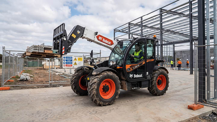 Bobcat TL35.70 construction telehandler operating in a confined commercial construction site in central Victoria, operator in cab, steel frame structure in background