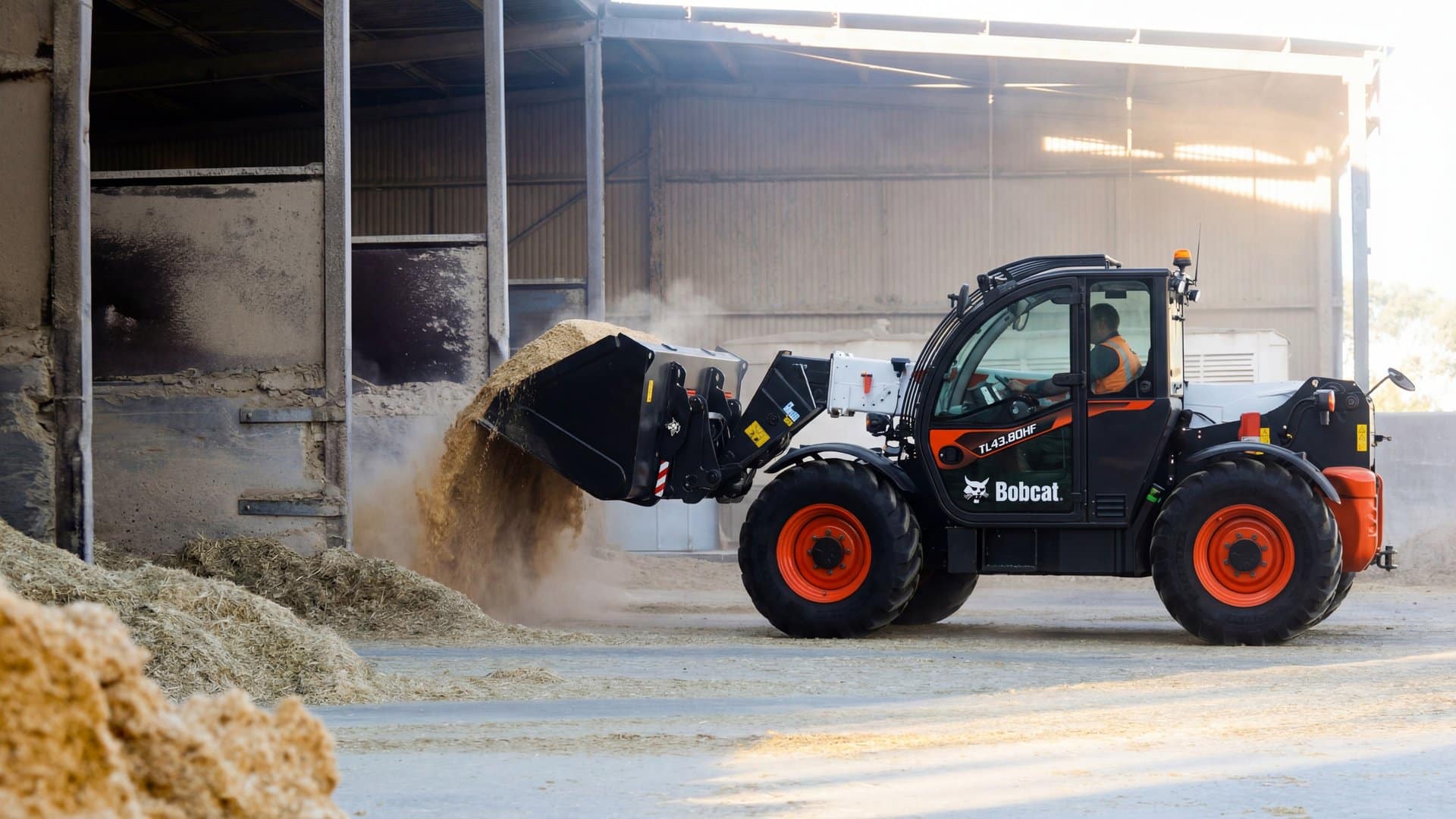 Bobcat TL43.80HF telehandler scooping feed from a commodity bunker at an Australian feedlot, operator visible in cab